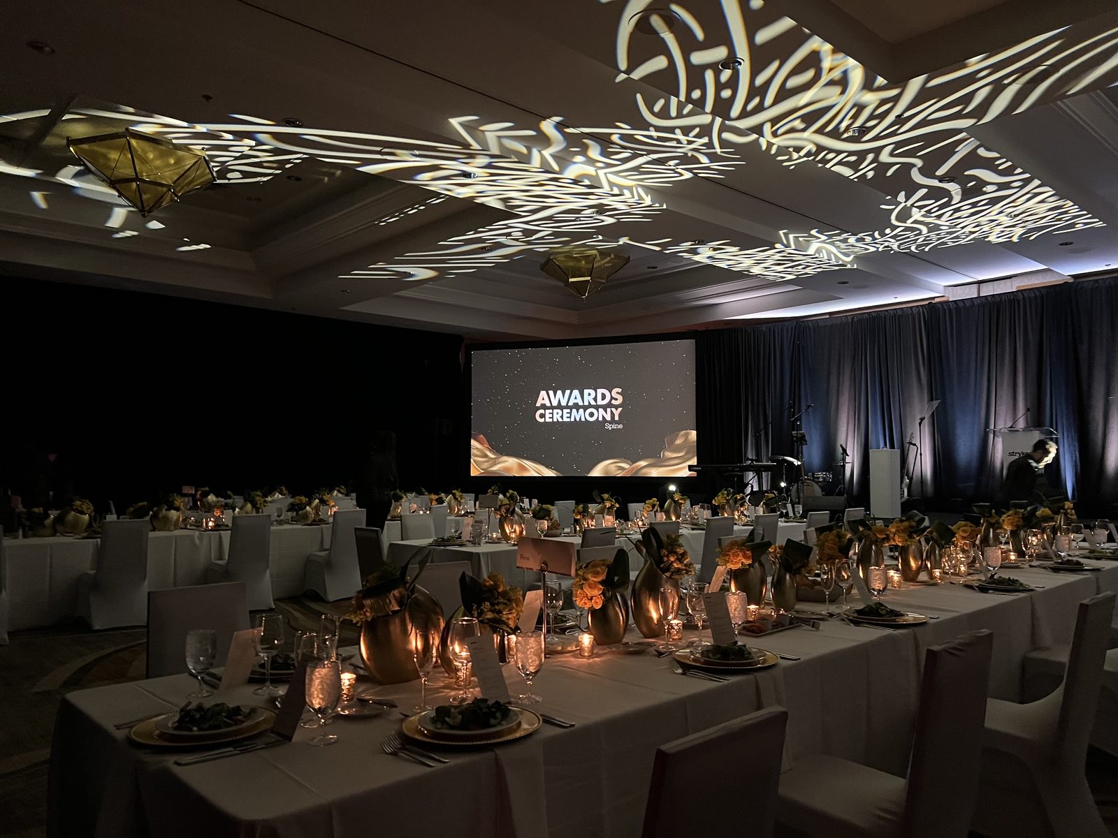 Awards Gala — Elegant stage design with warm lighting and IMAG screens for an awards banquet.