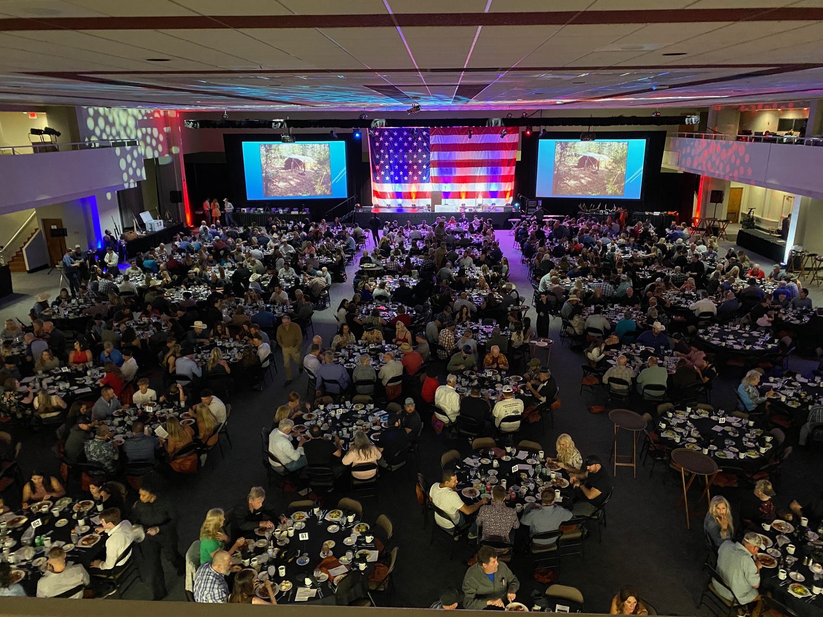 Gala Banquet Production — Dual projection screens, stage backdrop and uplighting for a large seated dinner.
